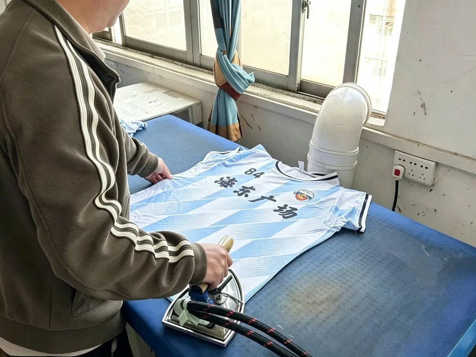 Worker ironing and heat-pressing a finished jersey