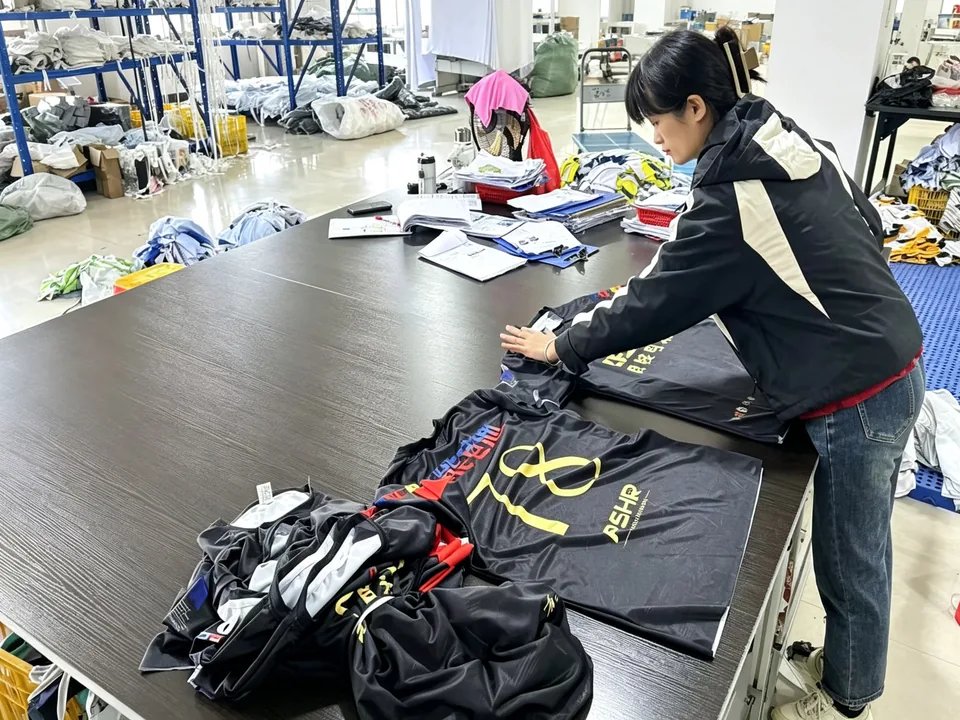Quality inspector checking printed jerseys on a light table